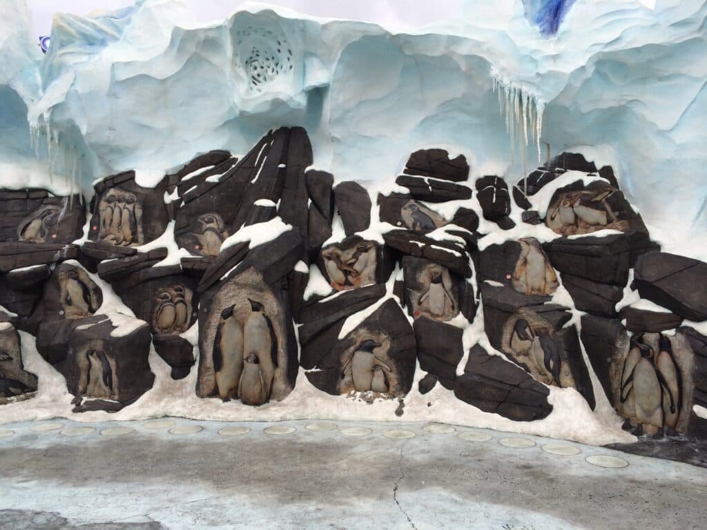 escultura em pedra que mostra diversas famílias de pinguins em meio ao gelo na entrada da atração Antarctica no parque SeaWorld Orlando