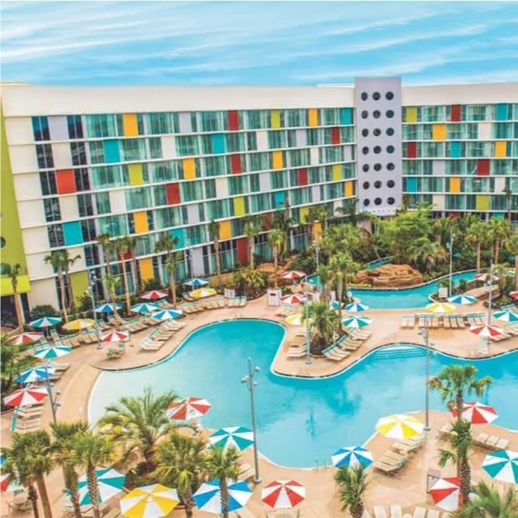 Hotel Cabana Bay da Universal Orlando Resort, com sua construção colorida e retrô. É possível a piscina a frente e diversos guarda sóis coloridos