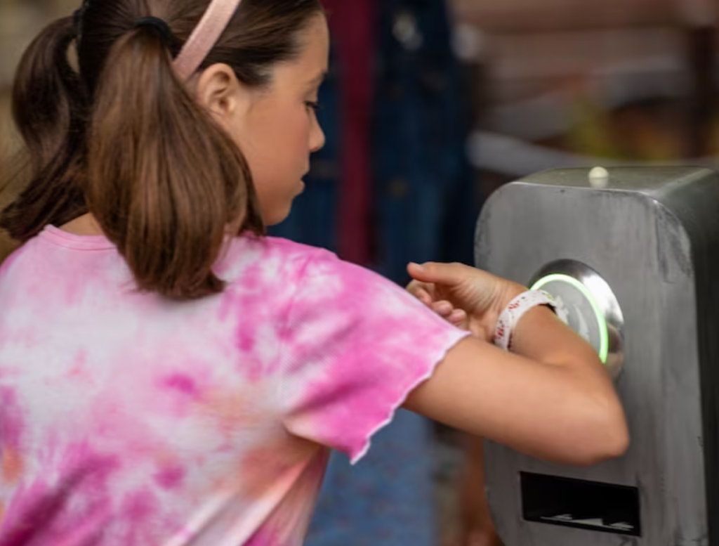 Criança com maria chiquinhas no cabelo usa sua Magic Band, pulseira tecnológica da Disney que serve como ingresso para scanear na entrada da atração pela fila do fura filas, a lightning lane