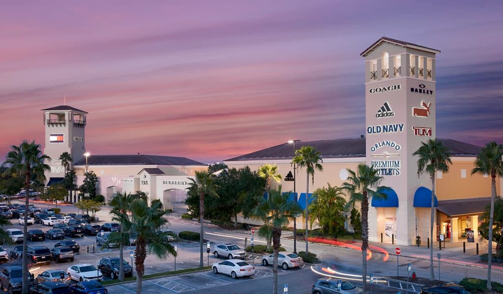 fachada e parte do estacionamento do outlet premium da Vineland em Orlando, na Flórida, onde é possível ver nomes de algumas marcas que são encontradas no centro comercial como Adidas, Coach, Old Navy, Puma, Tommy Hilfiger e outros